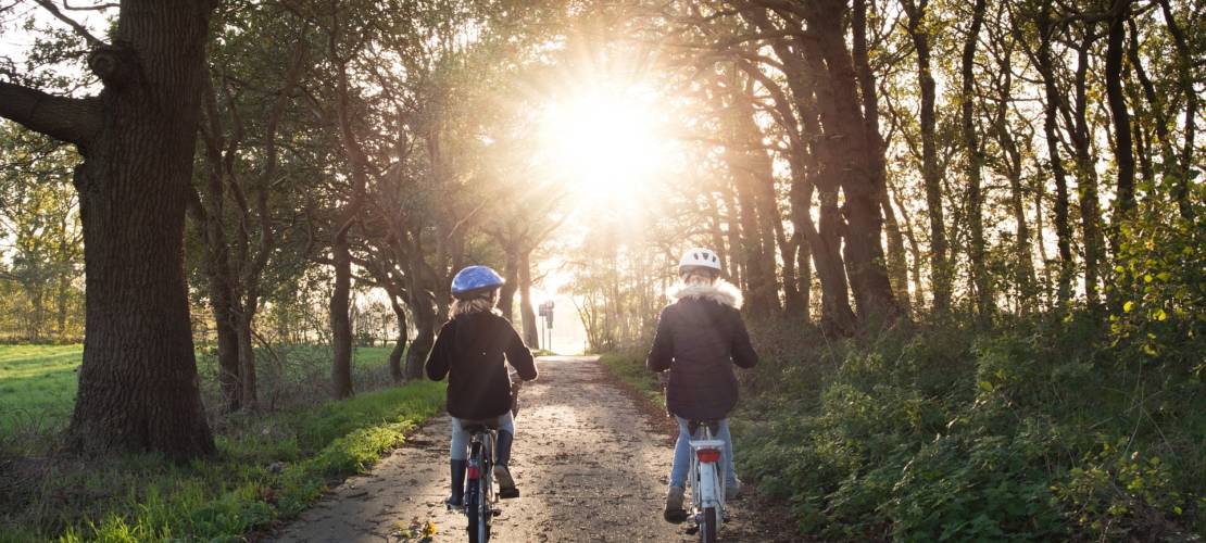 Un enfant et un homme à vélo sur une route de campagne
