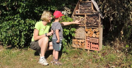 Animatrice avec un enfant devant un hôtel à insecte