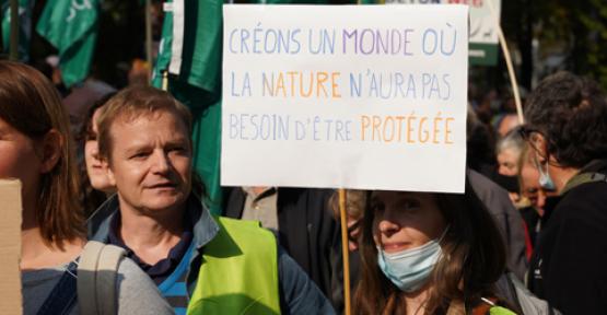 Manifestants avec une pancarte "Créons un monde où la nature n'aura pas besoin d'être protégée".